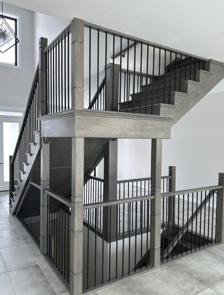 Grey wood staircase with black metal railings and multi-level landing