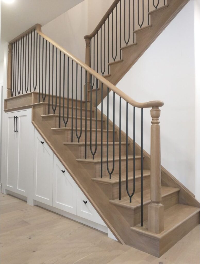 Light wood staircase with black metal balusters and matching handrail