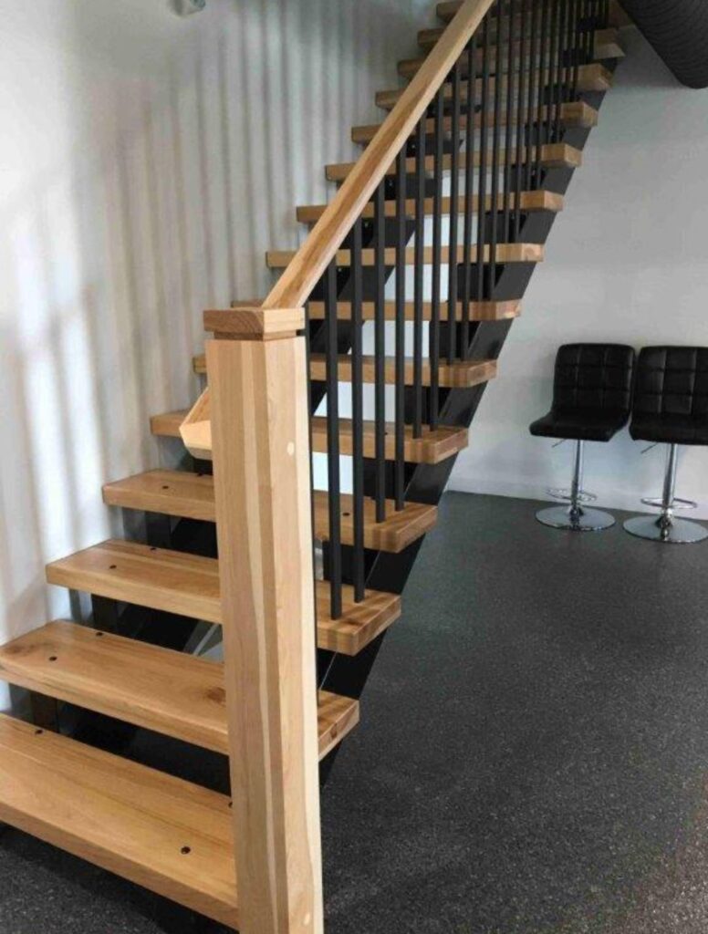 Open-riser wood staircase with black metal railings