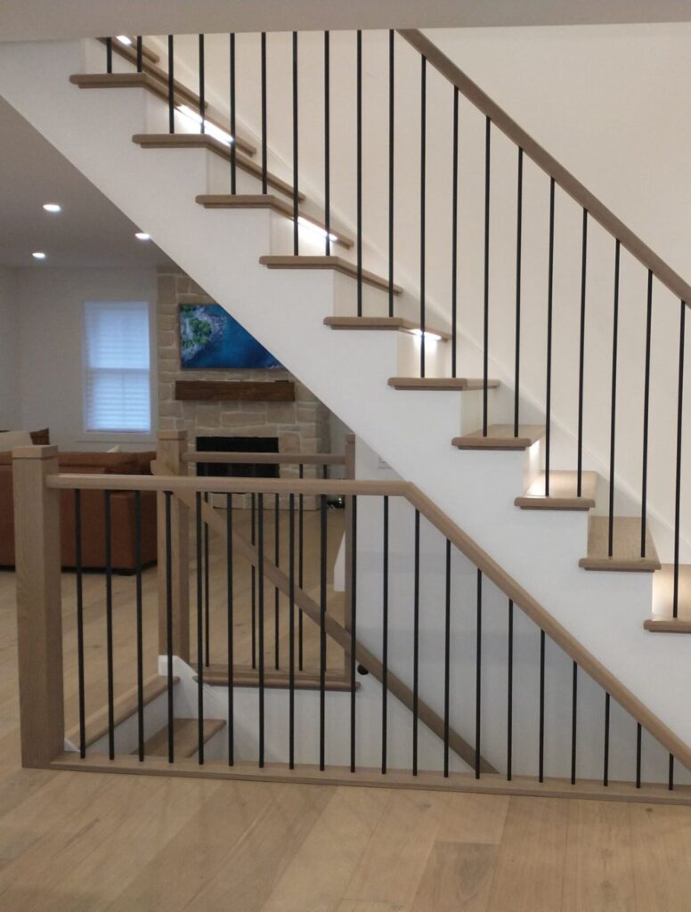 Wood tread staircase with black metal railings in a bright interior