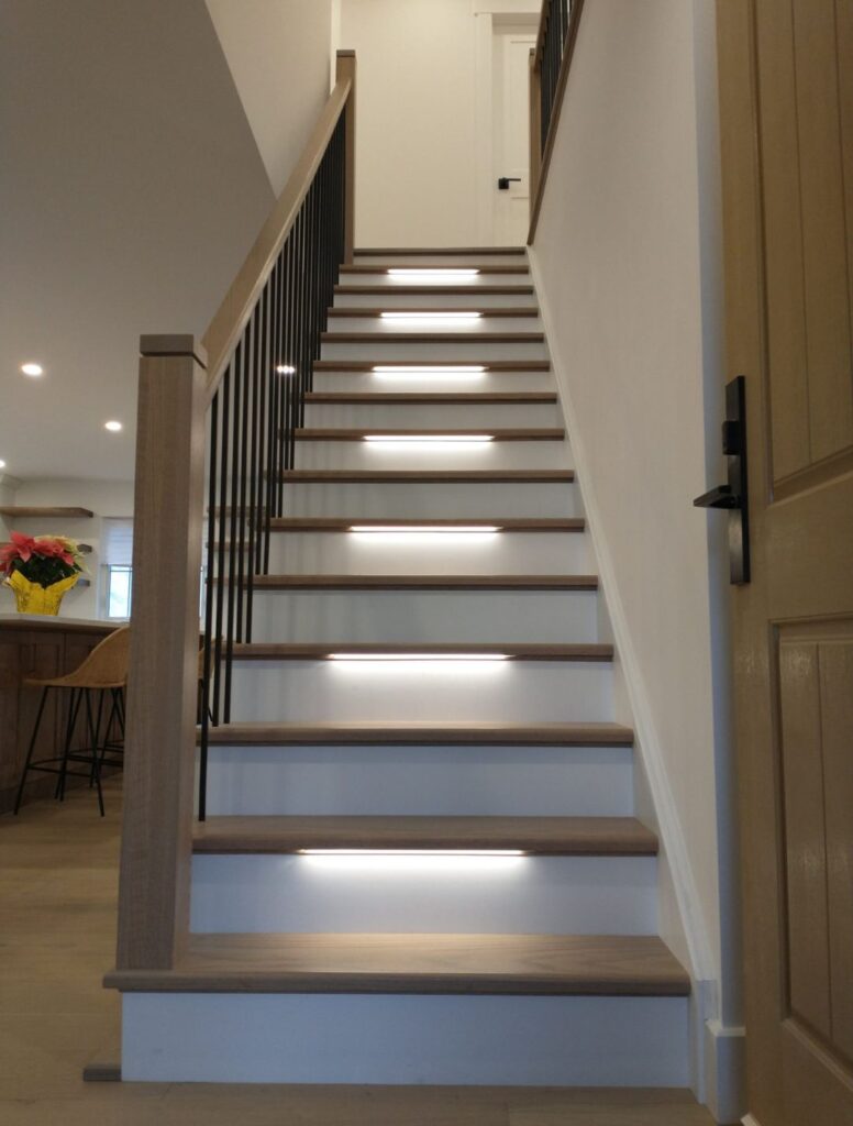 Modern staircase with illuminated steps and dark handrail
