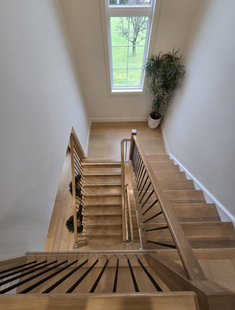 Light wood staircase viewed from the upper landing with matching railings