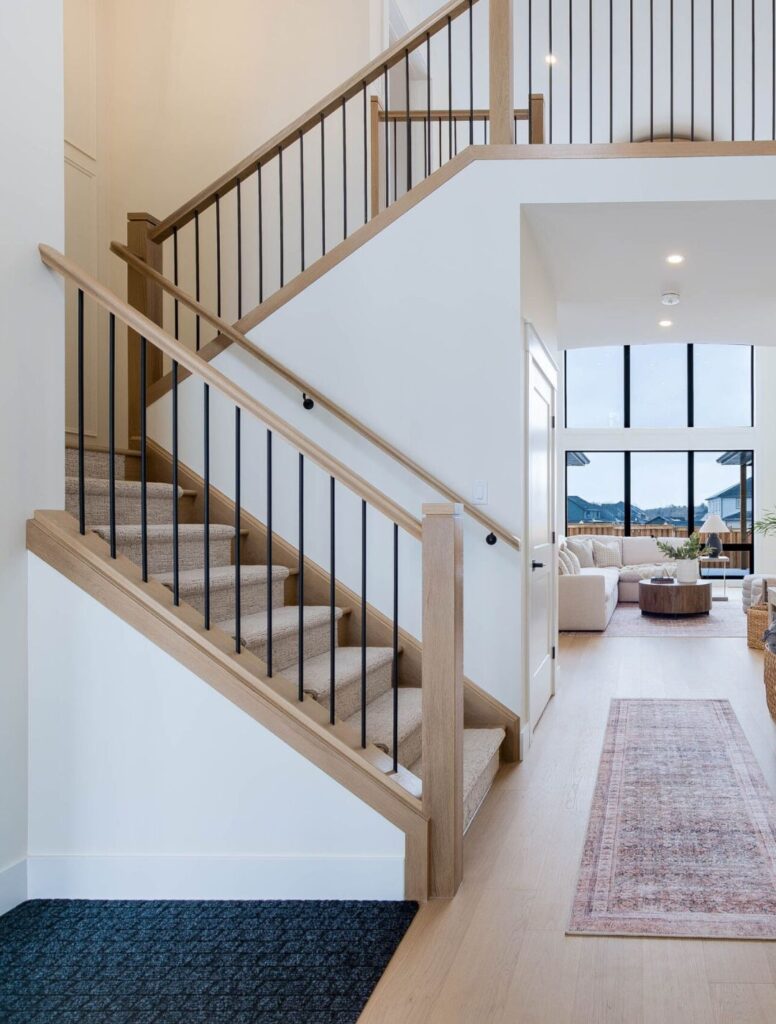 Light wood staircase and landing with black metal balusters in a bright interior