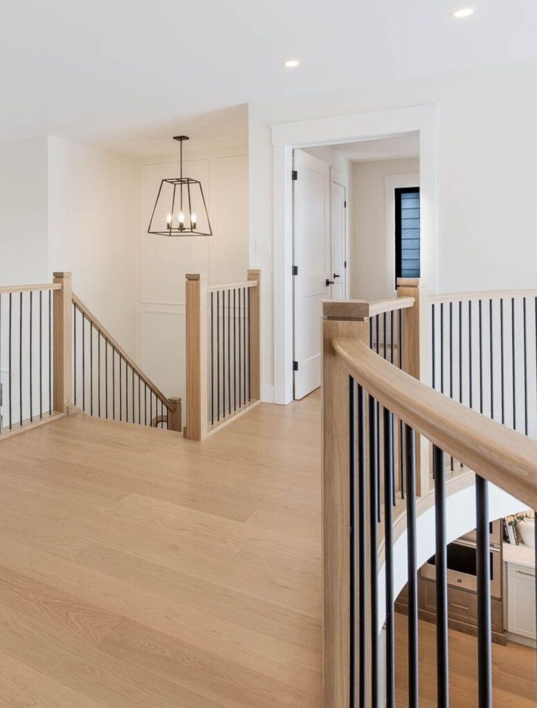 Light wood landing with matching handrail and black metal balusters