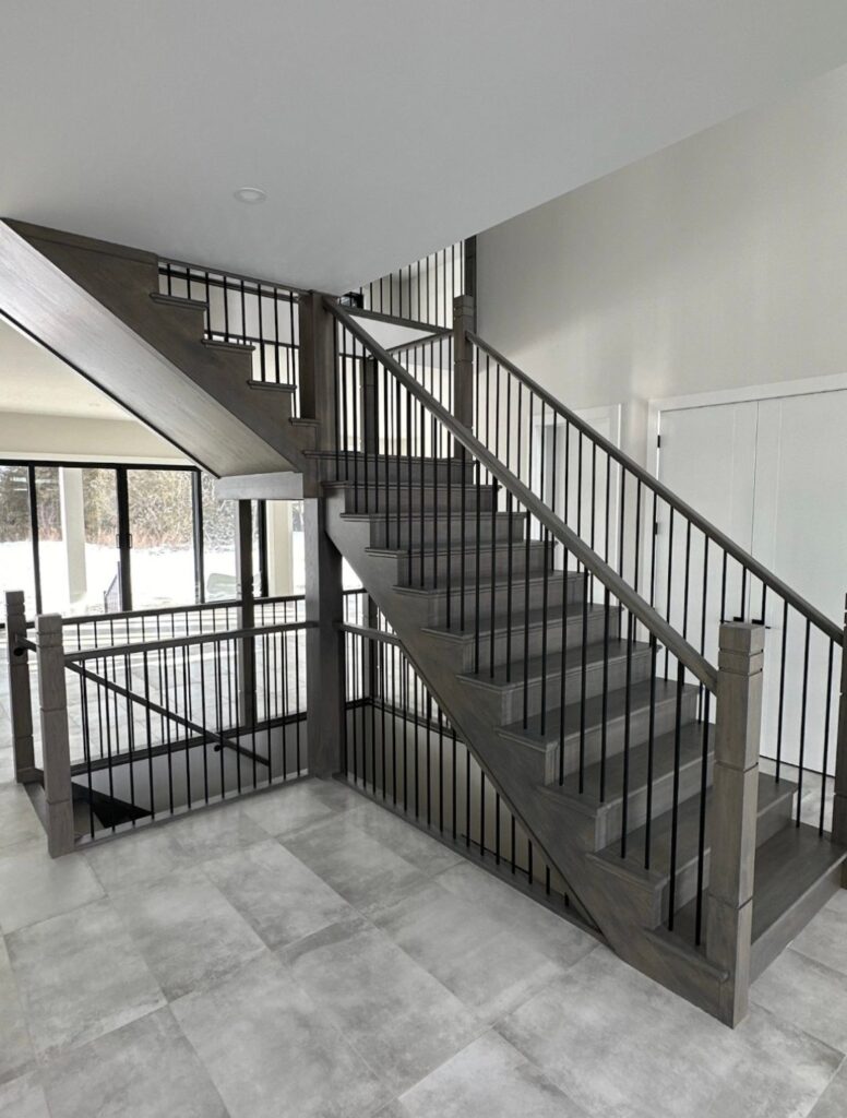 Grey staircase with black metal railings in a modern tiled interior
