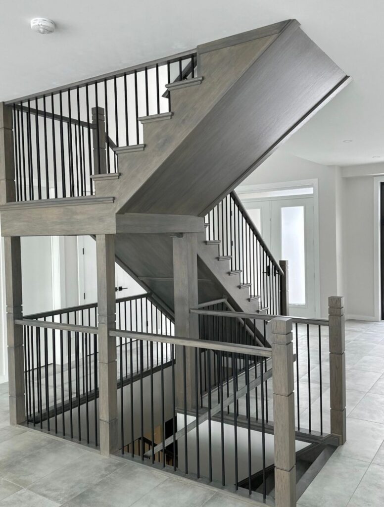 Grey multi-level staircase with black metal railings viewed from below