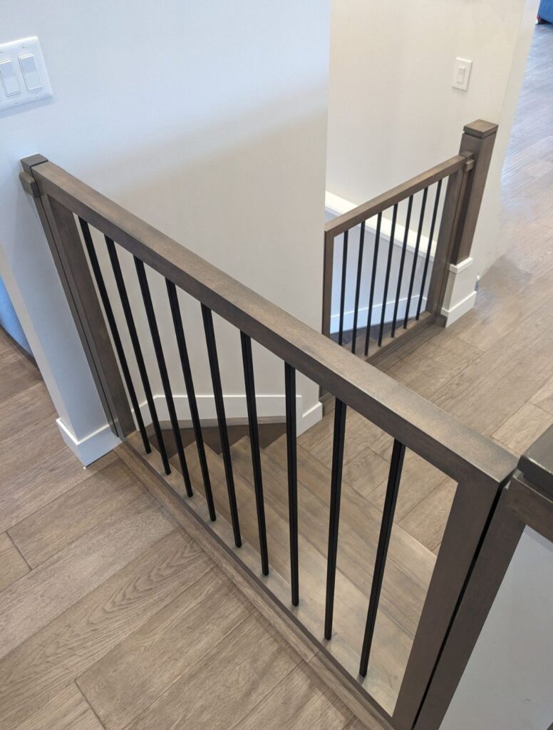 Dark wood landing railing with black metal balusters in a modern interior